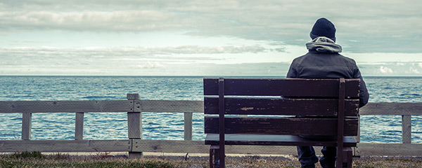 Man sitting on bench by the sea